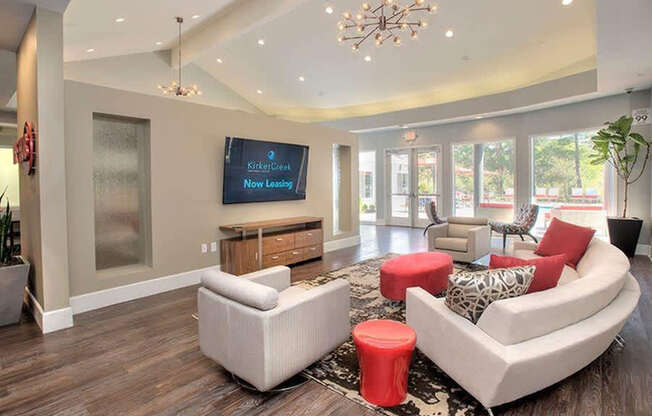 A living room with a white couch, a red ottoman, and a chandelier.