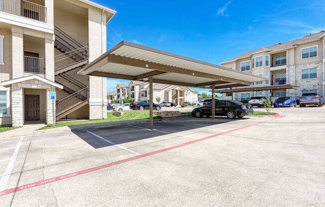 A parking lot with a covered area and a building in the background.