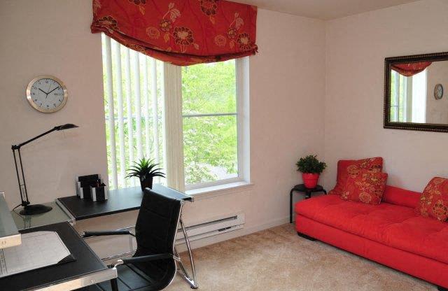 a living room with a red couch and a desk