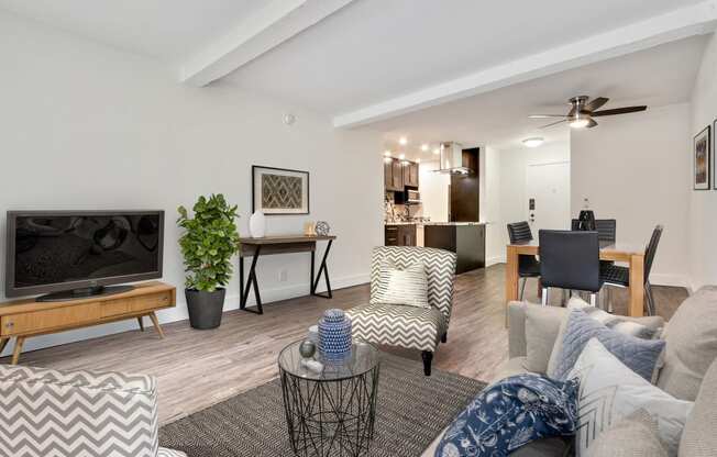 Gorgeous interior of a one bedroom, dining are with ceiling fan, kitchen with breakfast bar, living room with woos inspired flooring throughout the unit