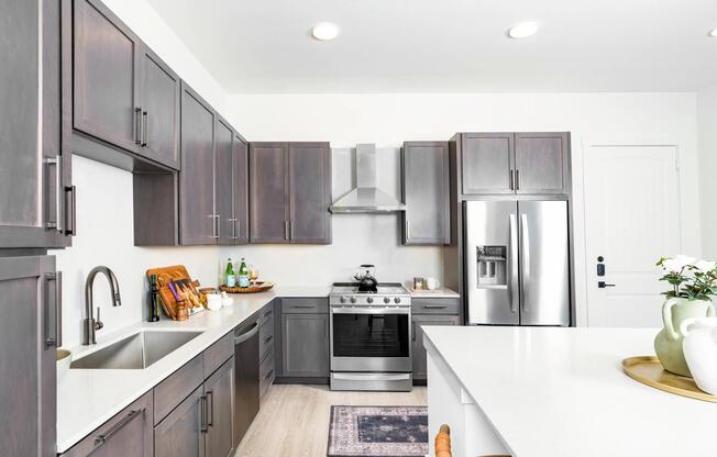 Kitchen with quartz countertops, shaker cabinetry, and stainless steel appliances arranged in a clean layout for cooking and gathering.