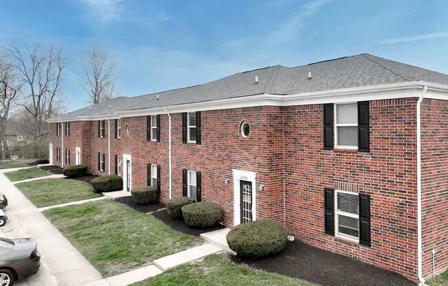 A red brick building with black shutters and a grey roof.