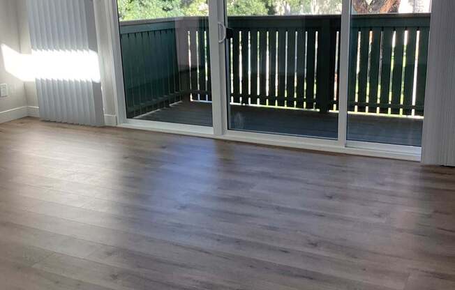 A room with wooden flooring and sliding glass doors.
