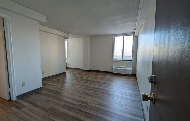an empty living room with wood floors and a window