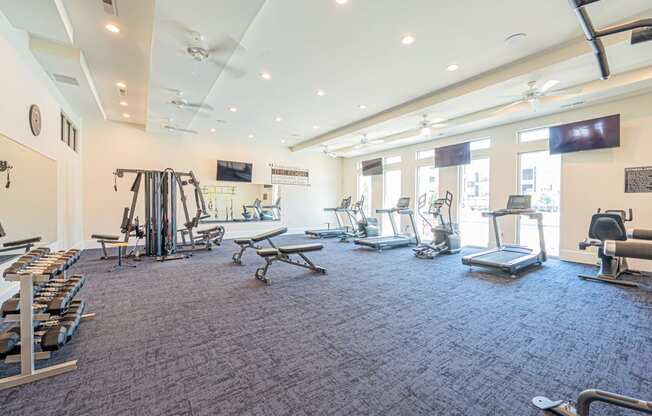a gym with weights and cardio equipment in a building with windows