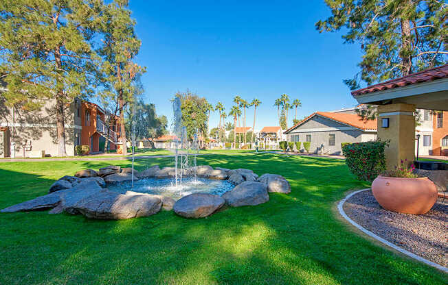 A garden with a fountain and a large pot.