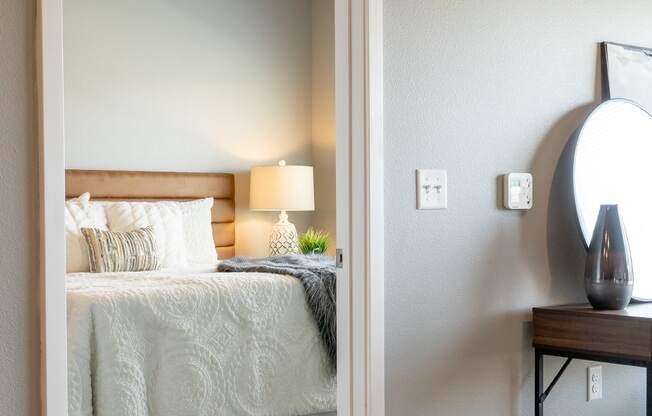 a bedroom with a bed and a nightstand and a mirror