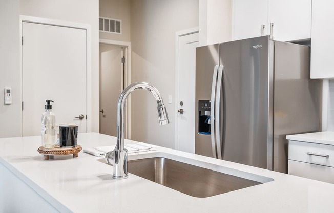 a kitchen with white countertops and a stainless steel refrigerator