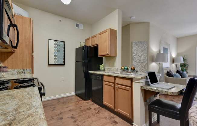 a kitchen and living room with a laptop on the counter