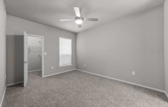 A room with a ceiling fan and carpeted floor.