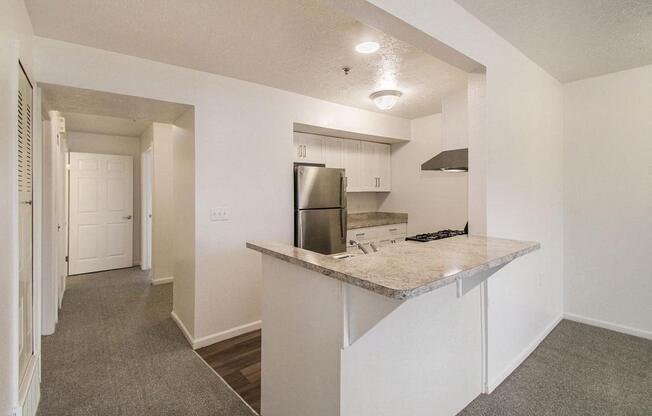 A kitchen with a breakfast bar and a stainless steel refrigerator at Brentwood Park Apartments, La Vista, Nebraska