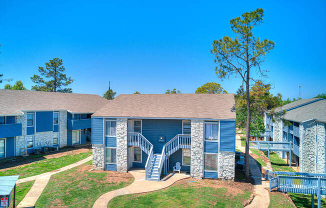 our apartments feature a spacious courtyard with trees and a blue building with stairs