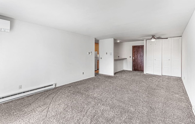 A room with a carpeted floor and a ceiling fan.