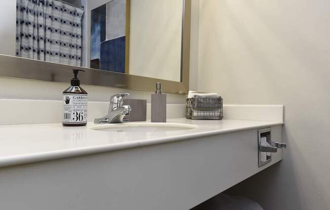 A white sink with a soap dispenser and a mirror above it.