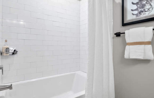 A white bathroom with a white tub and a white shower curtain.