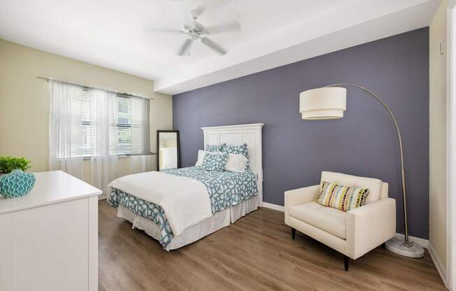 a bedroom with a bed and a chair and a ceiling fan