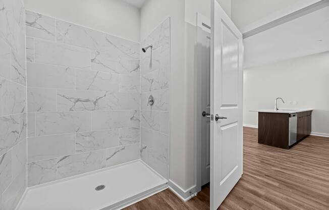 A bathroom with a marble tile shower and a white bathtub.