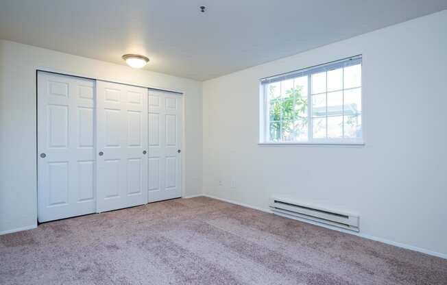 a bedroom with two closets and a window and carpet