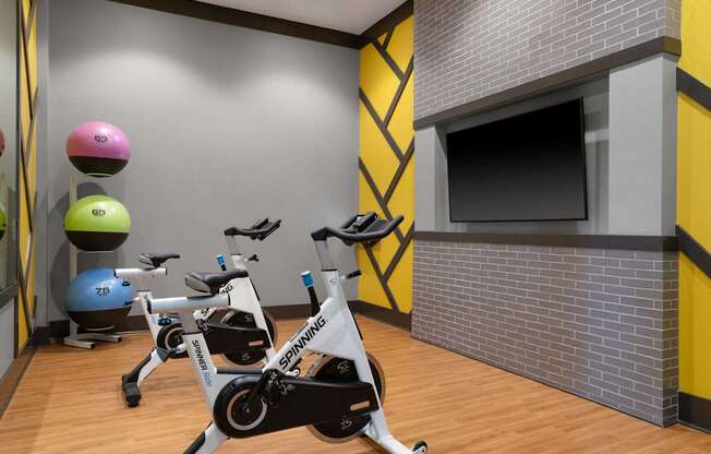 A Spinning bike is in the foreground of a brightly colored gym.