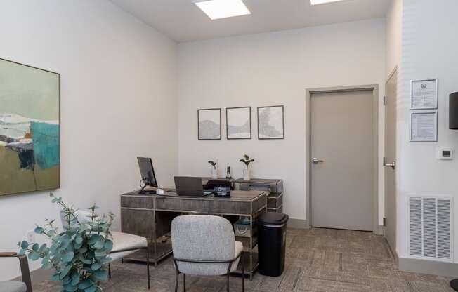 a desk with a laptop computer and a chair in a room with white walls and gray carpet
