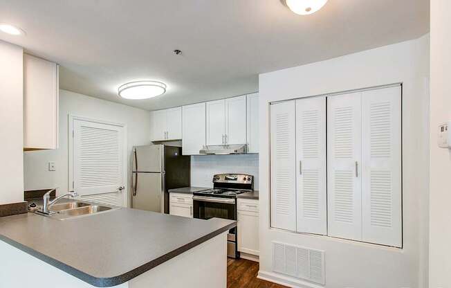 A kitchen with white cabinets and a black refrigerator.