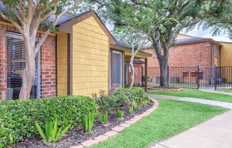 a house with bushes in front of a brick building