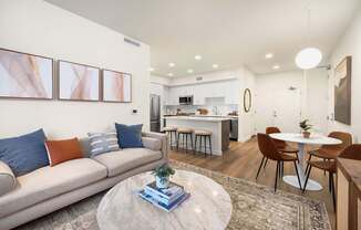 A modern living room with a grey sofa, a round coffee table, and a kitchen in the background at The Villas at Anacapa Canyon, Camarillo, 93012