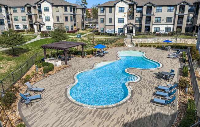 A large swimming pool with a wooden deck and lounge chairs.