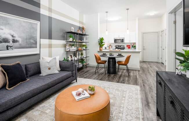 a living room with a couch a table and chairs and a kitchen in the background