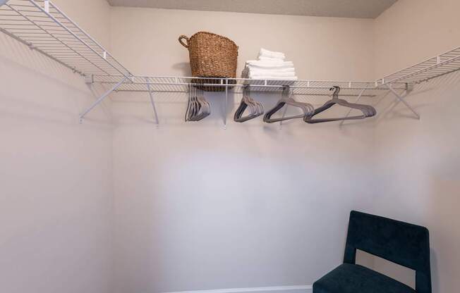 A chair sits under a clothes rack in a small room.