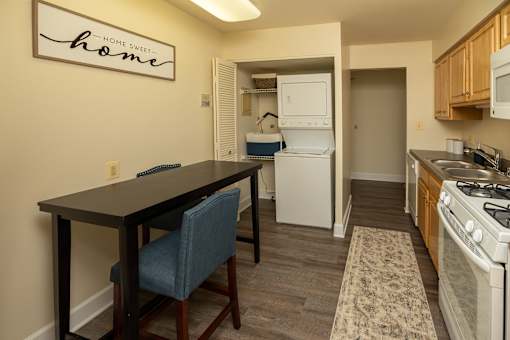 A kitchen with a table and chairs in front of a sign that says Home Sweet Home.