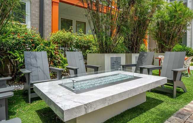 A modern outdoor seating area with a glass table and grey chairs.