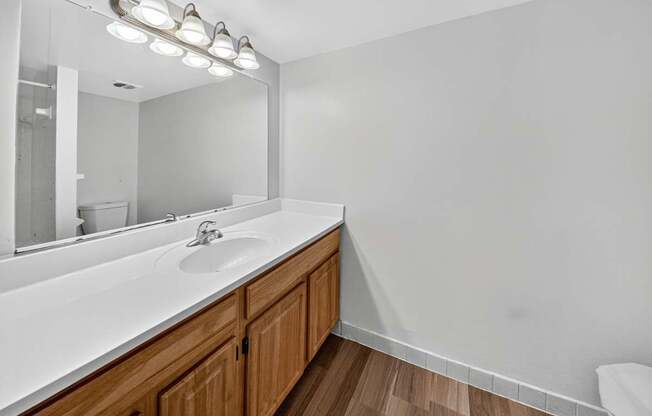 A bathroom with a white countertop and wooden cabinets.