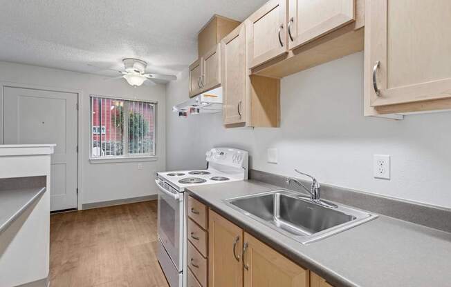 A kitchen with a stove, sink, and cabinets.