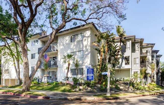 a white apartment building with palm trees and a blue sign