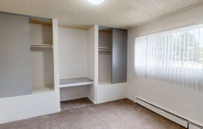 A room with a carpeted floor and a window with blinds.