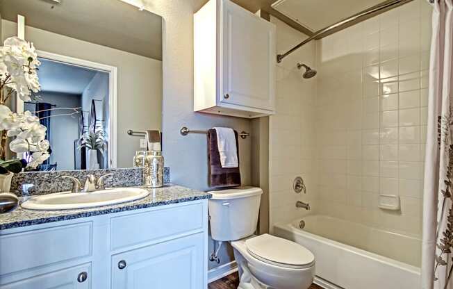 bathroom in one bedroom floorplan with white cabinets and granite countertops