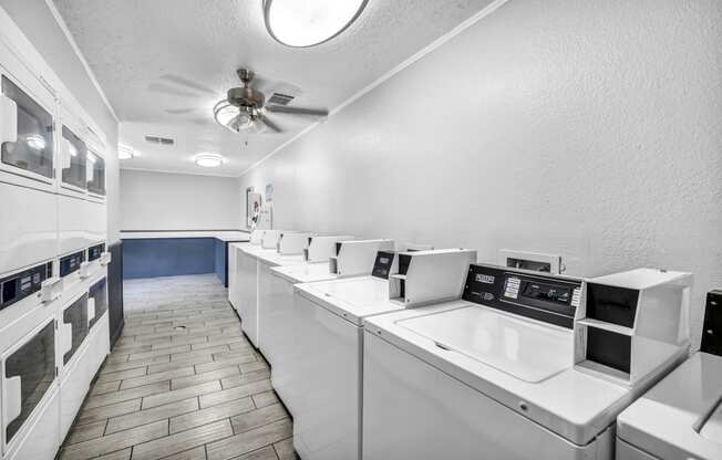 a laundry room with many washers and dryers and a ceiling fan