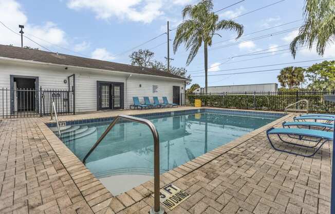 a swimming pool with chairs and a house in the background