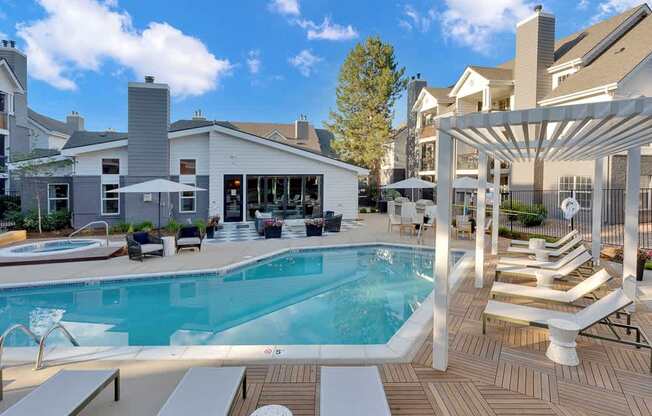 A large outdoor swimming pool with sun loungers and a pergola.