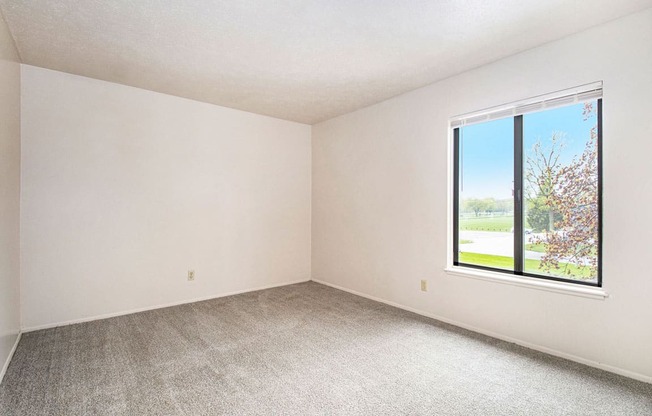 a bedroom with a large window and a carpeted floor