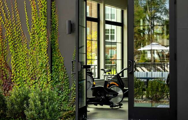 A yoga mat, a foam roller, a stability ball, and a resistance band are all laid out on a green mat outside a modern building.