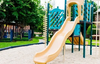 A playground with a yellow slide and a green slide.