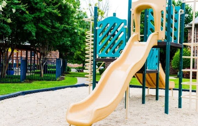 A playground with a yellow slide and a green slide.