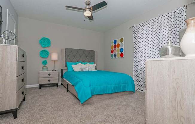 A bedroom with a bed, dresser, and ceiling fan at The Marq in Shreveport, LA