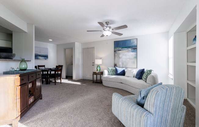 a living room with a couch and a chair and a ceiling fan