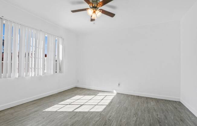 an empty living room with white walls and a ceiling fan