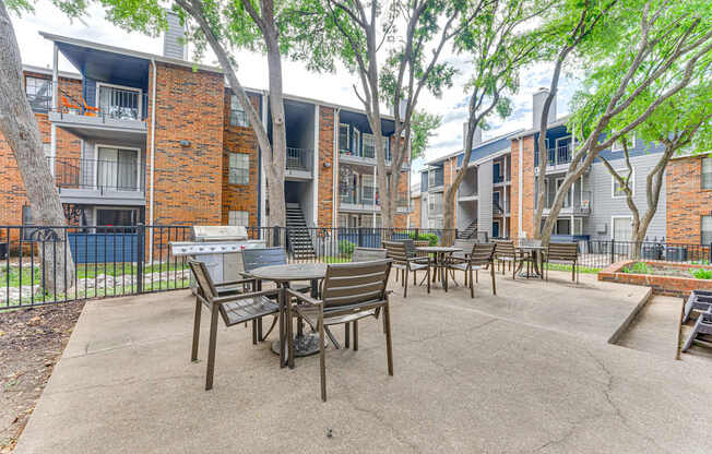 A patio with a table and chairs is surrounded by apartment buildings.
