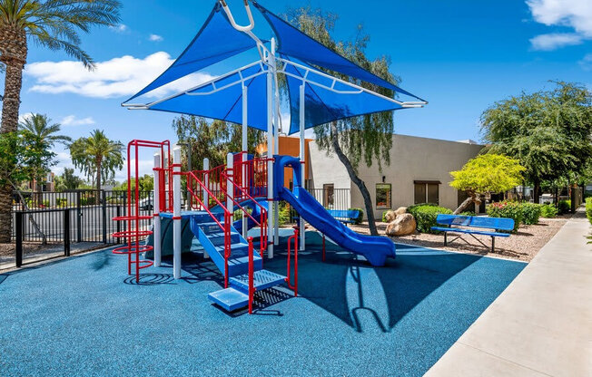 Community Playground with a Slide and Blue Canopy at Harmony at Surprise Apartments in Surprise, AZ.