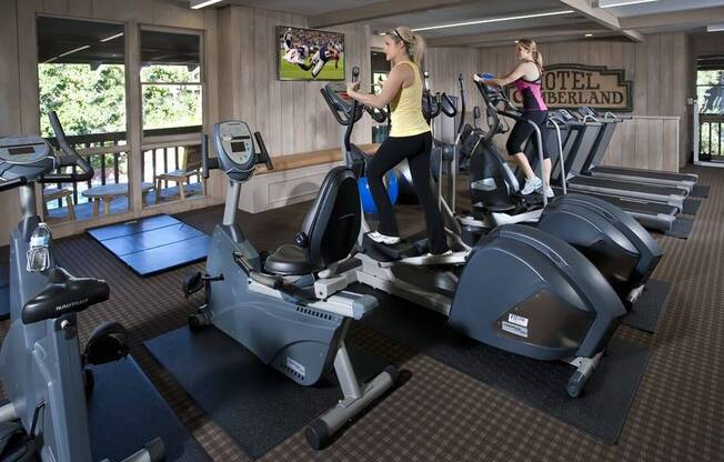 two women working out on exercise machines in a gym